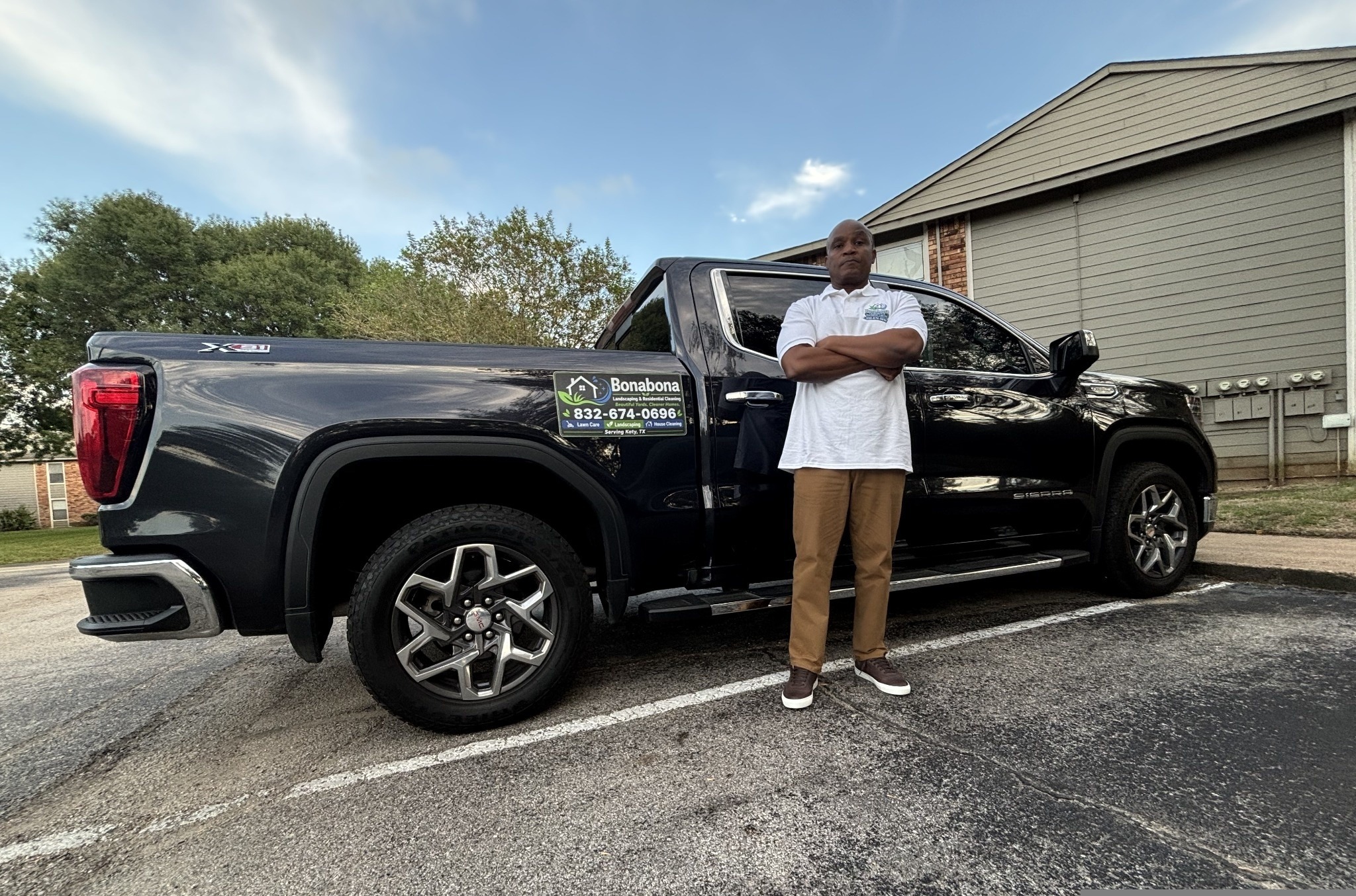 Bonabona's owner standing beside his GMC Sierra with the company's landscaping and cleaning sign